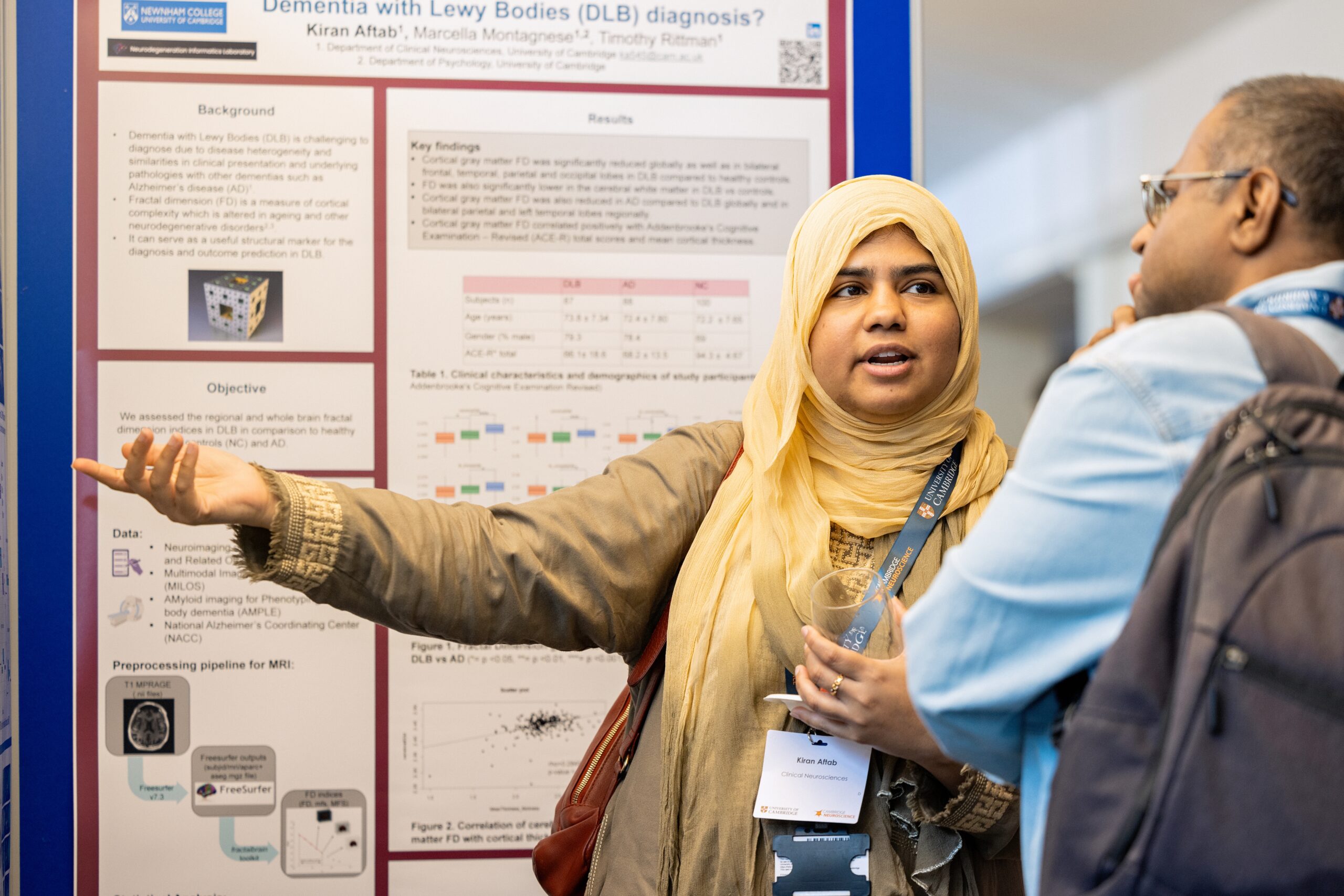 woman presenting a scientific poster with man listening to her
